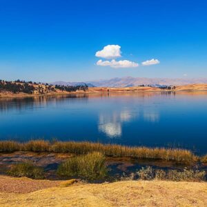 Panoramic view of Huaypo Lagoon mirroring the blue sky during an ATV tour in Cusco.